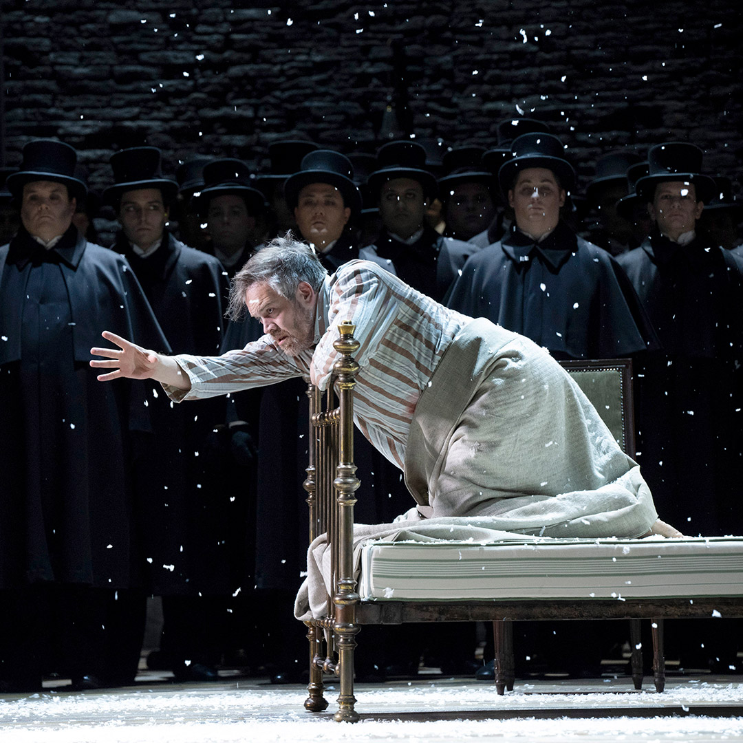 Amfortas, played by Audun Iversen, kneeling on a bed during a Glyndebourne production of Parsifal.
