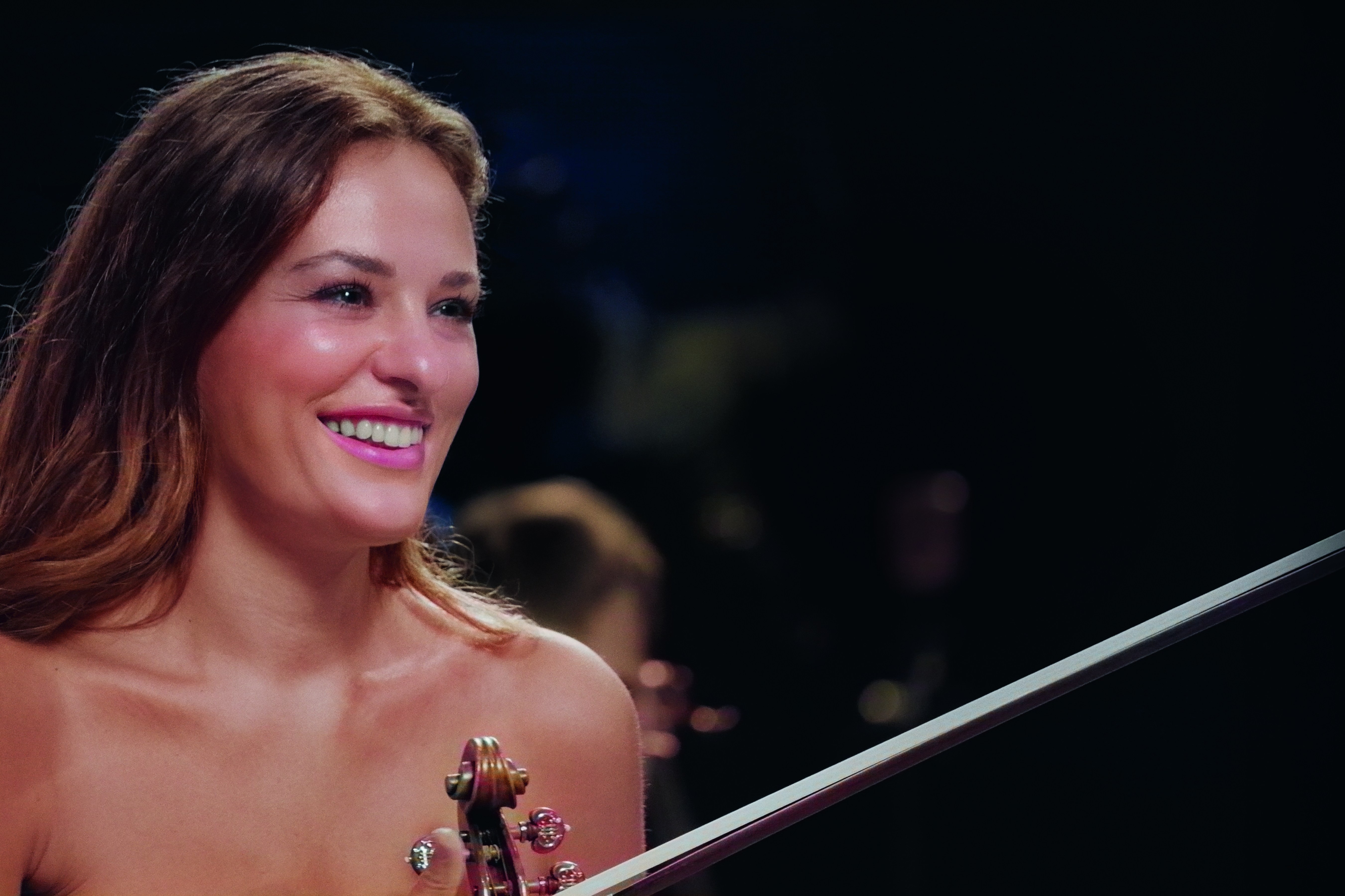 Nicola Benedetti smiling while holding a violin.