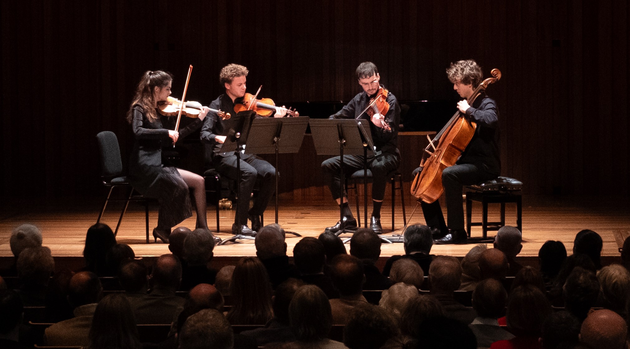 A string quartet performing on stage to an audience.